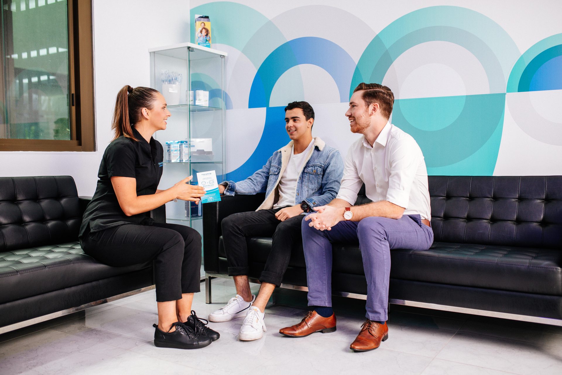 Toowong Orthodontics team member talking to two patients about what to do when the orthodontist is closed